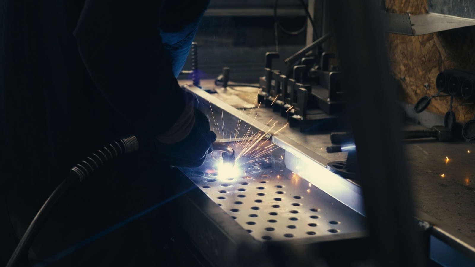 Fabricator welding a perforated metal panel in the shop