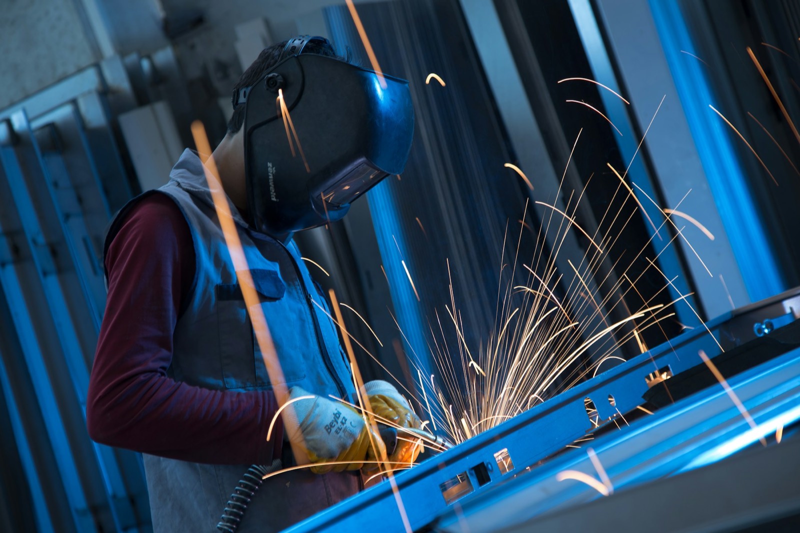Welder working on a metal part with sparks flying